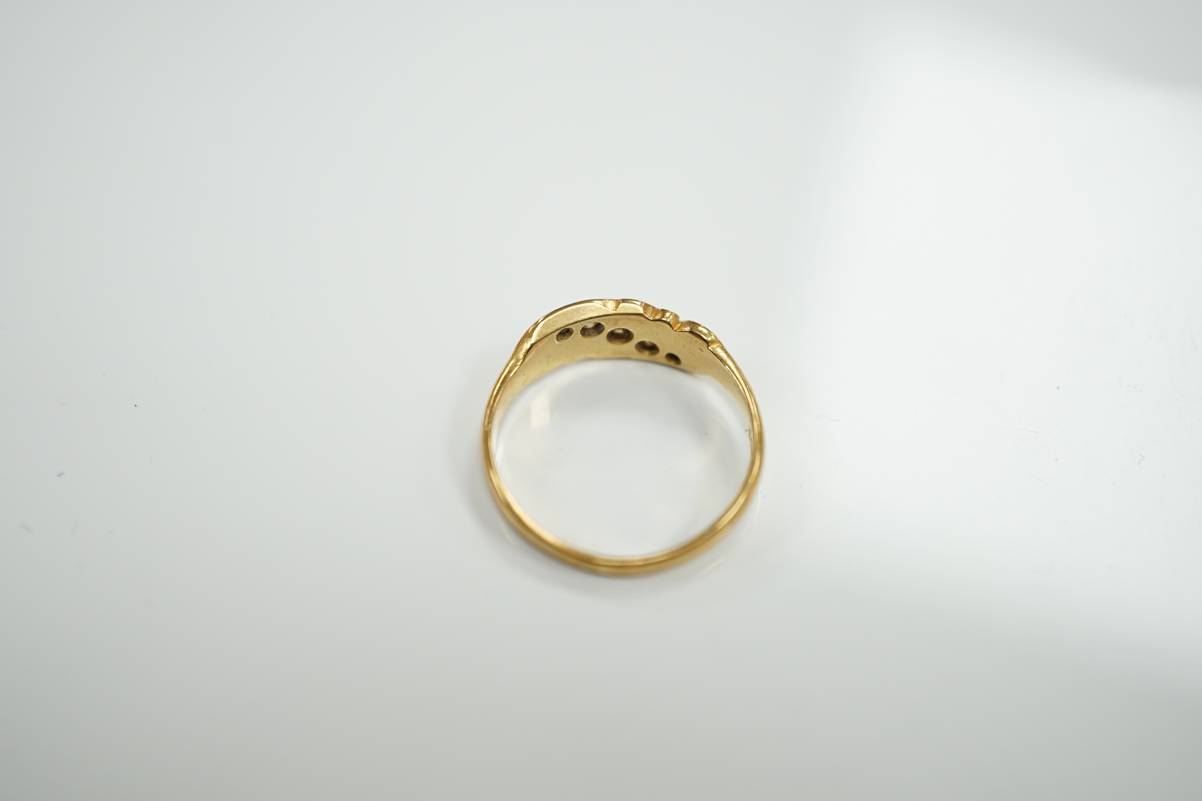 An early 20th century 18ct and graduated five stone set diamond ring, with scrolling setting, size Q, gross weight 3.4 grams.